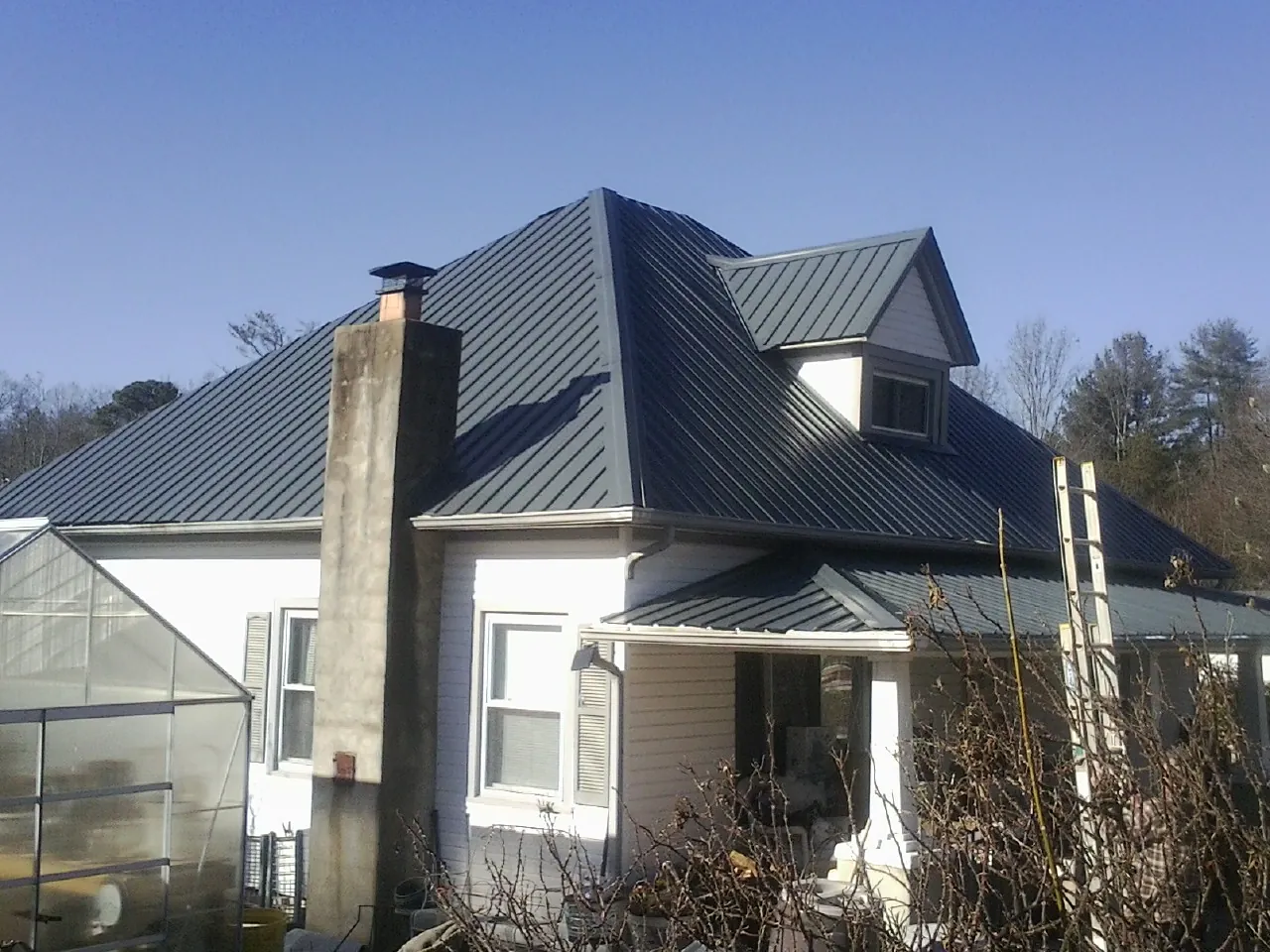 Dark blue standing seam metal roof on a white farmhouse with dormer — Slate & Tile Roof Repair by Roofing Brothers in Beavercreek