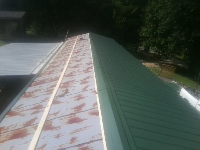 Old rusted panels beside newly installed green metal roofing — Wind Damage Roof Repair by Roofing Brothers in Beavercreek