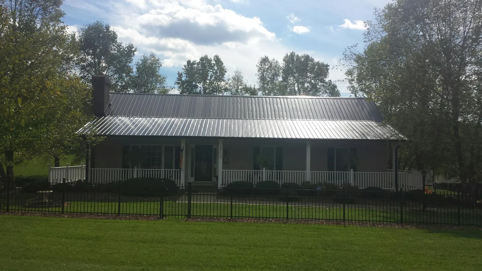 Gray metal roof on a brick ranch with a full width front porch — Gutter Guard Installation work by our crew in Beavercreek