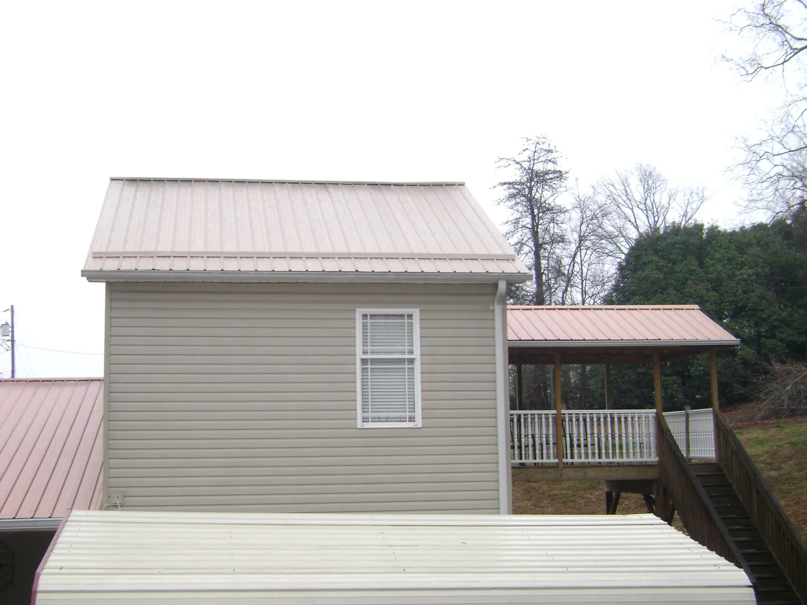 Tan metal roofs on a two story addition and attached porch, from a Roof Replacement job in Beavercreek