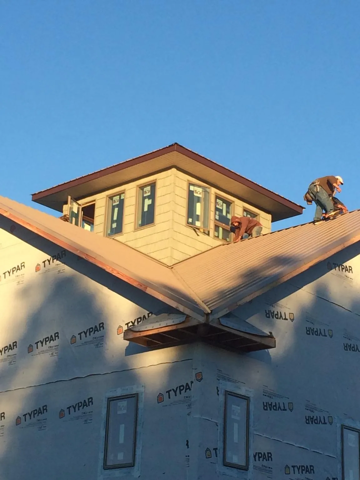 Roofers working around a rooftop cupola on a new metal roof at sunset — Roof Waterproofing in Beavercreek by Roofing Brothers